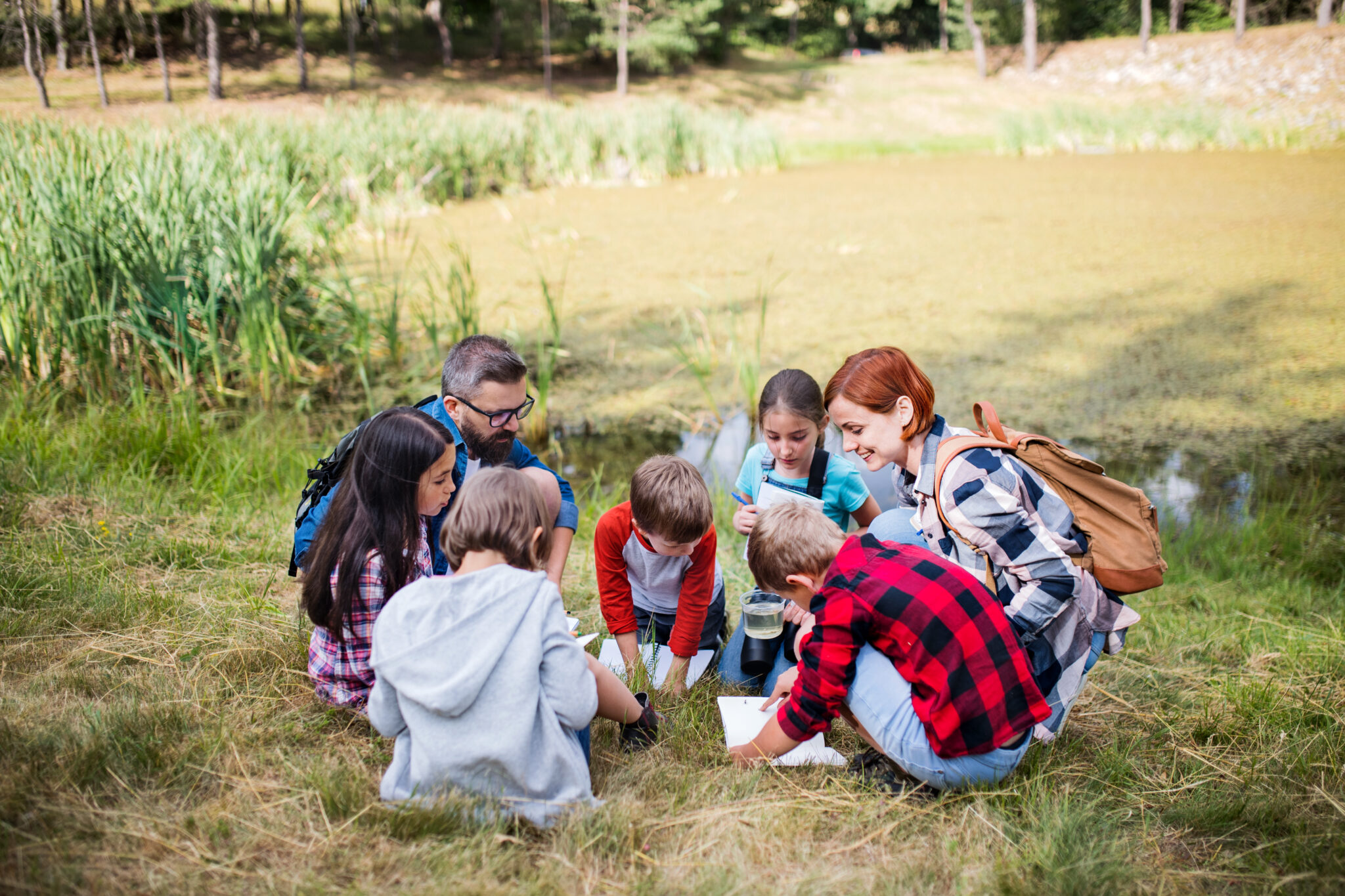Children and teachers exploring nature by a pond