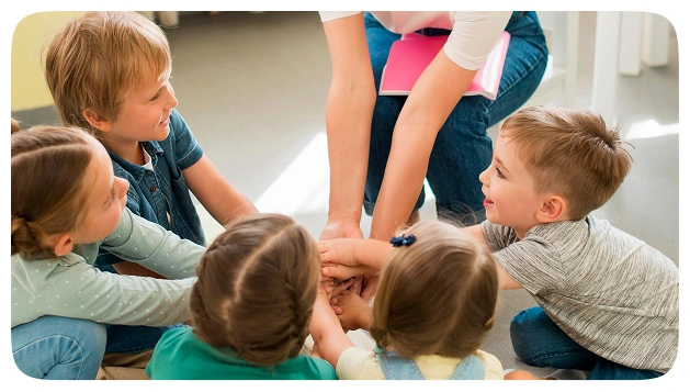 Children and a teacher putting their hands together in a circle
