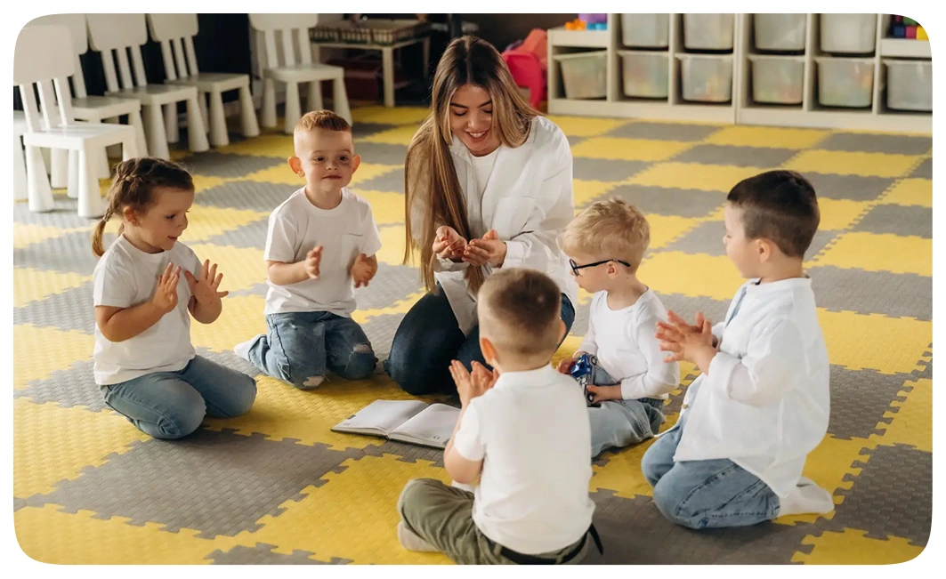 Teacher clapping along with children on a play mat